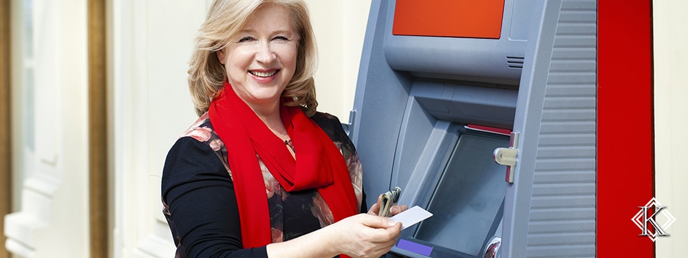 Senhora sorrindo e recebendo pagamento em caixa eletrônico