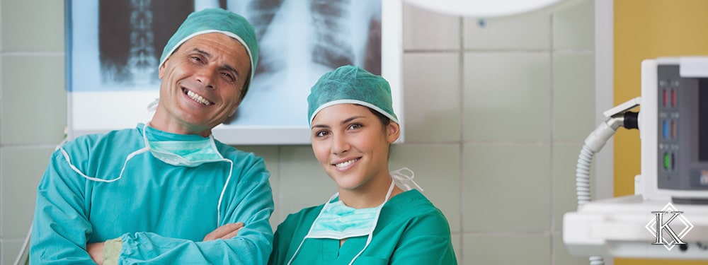 Médico e médica sorridentes em frente à exames de raio x, representando a possibilidade de continuar trabalhando mesmo após a obtenção da aposentadoria especial.