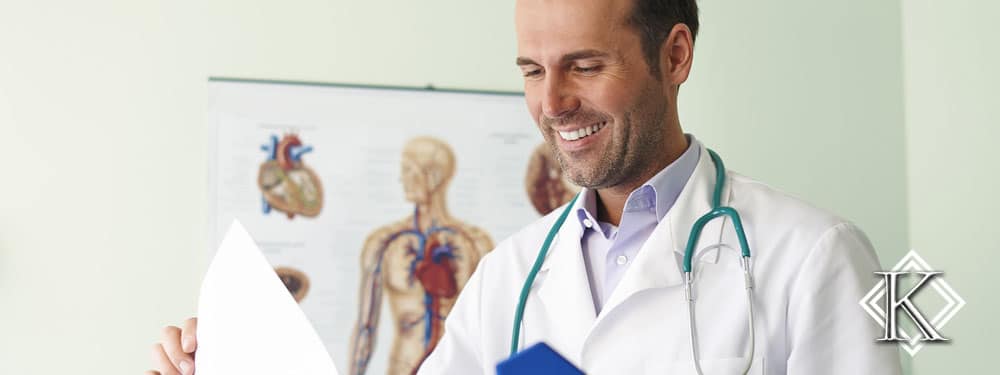 Médico sorrindo, com estetoscópio pendurado no pescoço e analisando uma pasta
