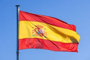 A imagem mostra a bandeira da Espanha, hasteada, balançando com o vento. Ilustra o texto sobre Acordo Previdenciário entre Brasil e Espanha.