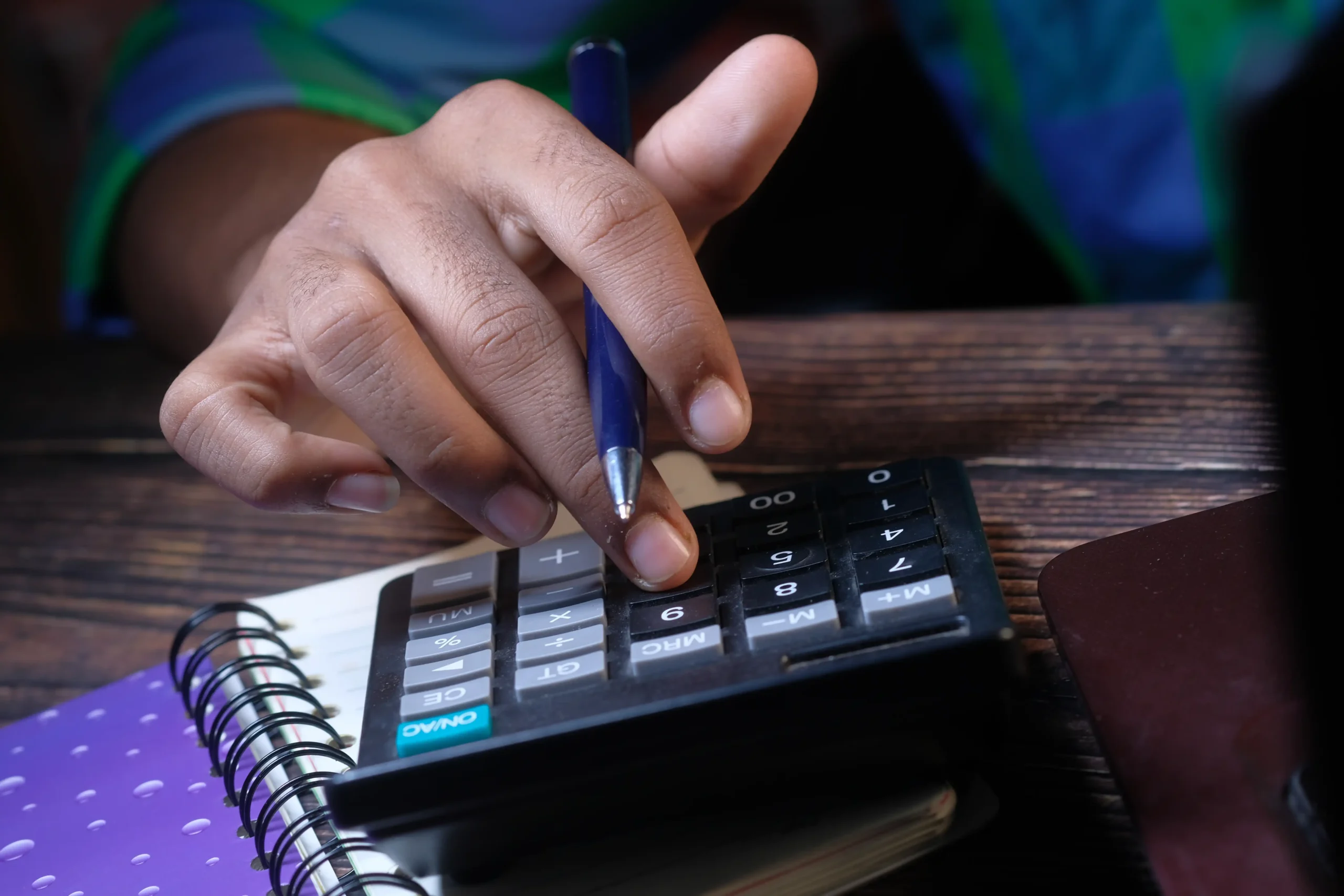 A imagem mostra uma vista aproximada de um homem usando uma calculadora. Ilustra o texto sobre valor da pensão servidor federal.