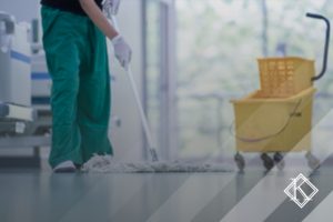 A imagem mostra um funcionário de hospital limpando o chão, e ilustra a publicação 