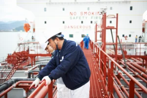 A imagem mostra dois trabalhadores em um navio de petróleo. Ilustra o texto sobre Aposentadoria Especial na Engenharia de Petróleo e Gás.