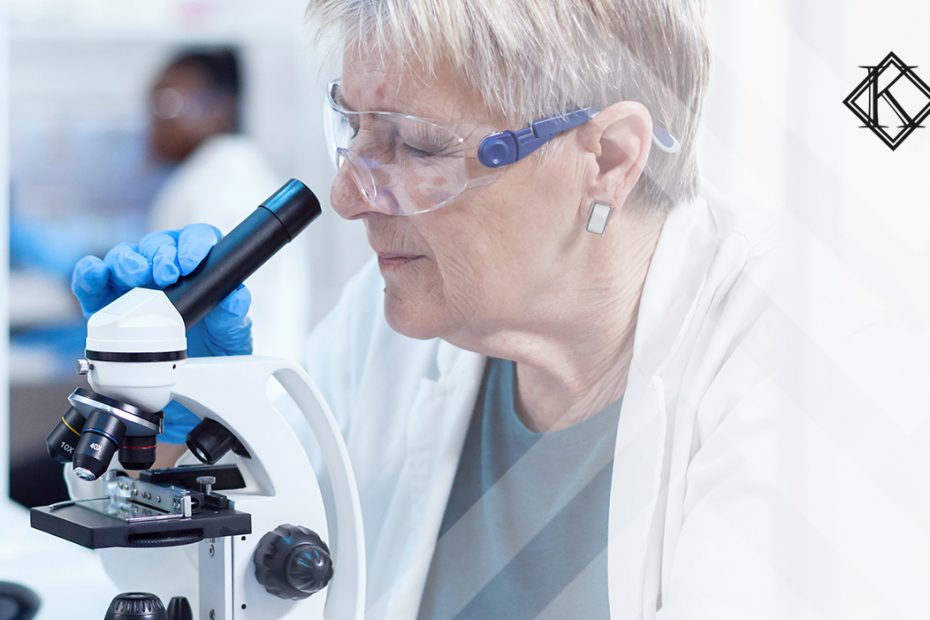 A imagem mostra uma mulher utilizando um microscópio, e ilustra a publicação " Aposentadoria especial do toxicologista: quais são as regras?", da Koetz Advocacia.