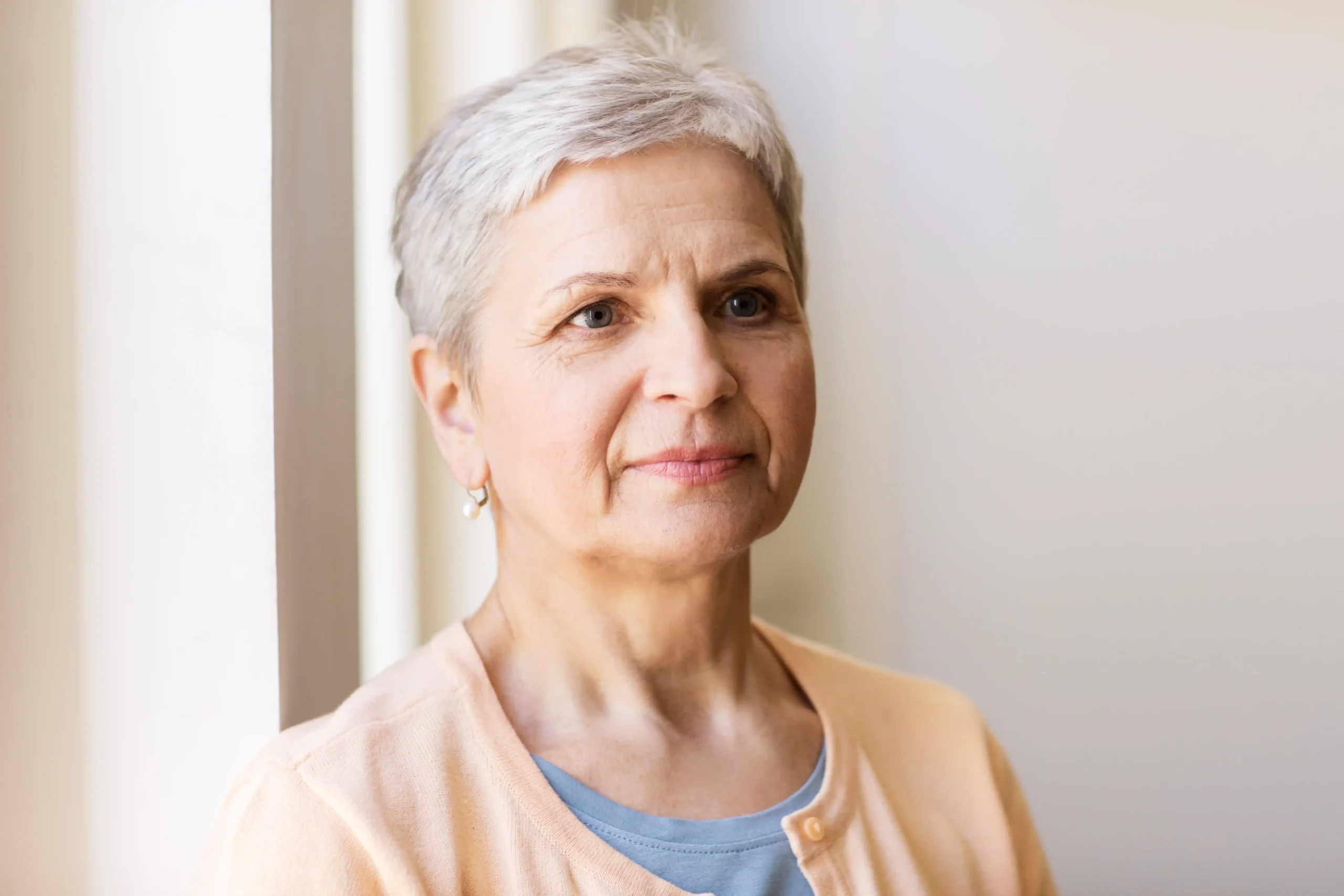 A imagem mostra uma mulher madura, de cabelos brancos e curtos, olhando para o horizonte. Ilustra o texto sobre pensão vitalícia.