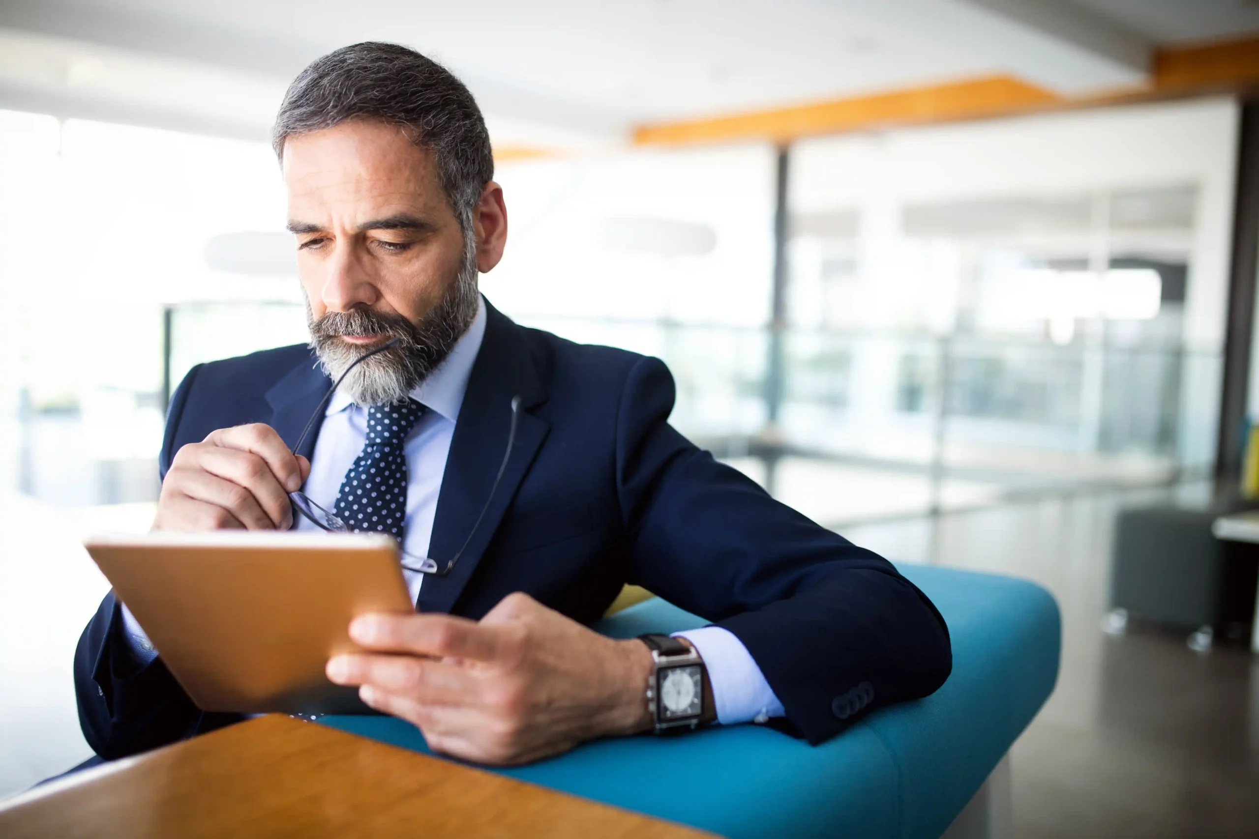 A imagem mostra um empresário sênior com tablet digital em um escritório moderno. Analisando, como pagar inss atrasado de empregado.