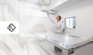 A imagem mostra uma profissional da saúde próxima a um aparelho de raio-X, e ilustra a publicação 