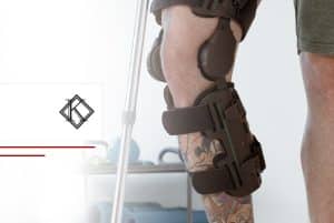 A imagem mostra uma pena em foco, em um processo de fisioterapia e recuperação. A perna é de um homem, é tatuada e está envolta em um aparelho de fisioterapia e ilustra o post 