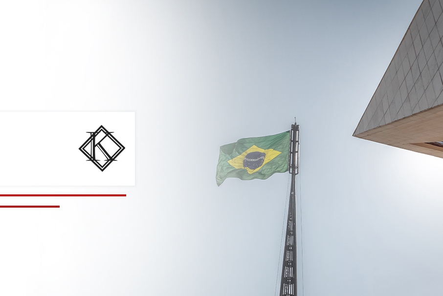 A imagem mostra uma bandeira do Brasil hasteada, se movimentando com o vento e ilustra o post "Atividades exclusivas de brasileiros: lista e alternativas para estrangeiros!" da Koetz Advocacia.
