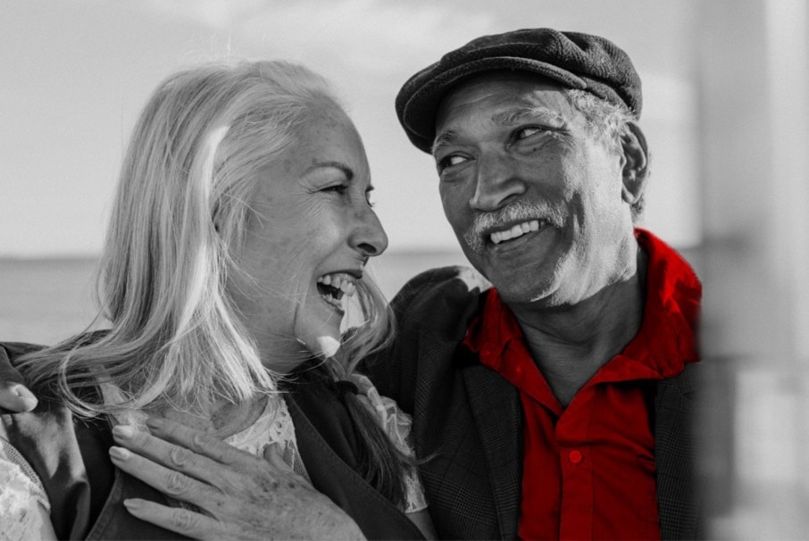 A imagem mostra um casal de idosos, abraçados. Eles estão sorrindo.