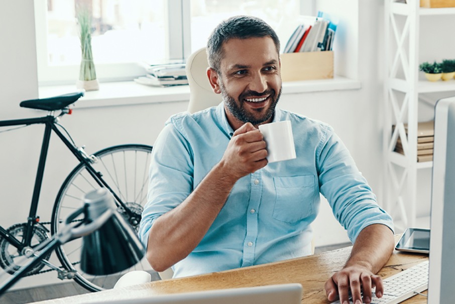 A imagem mostra homem sorrindo enquanto digita em seu computador. A imagem ilustra o texto 