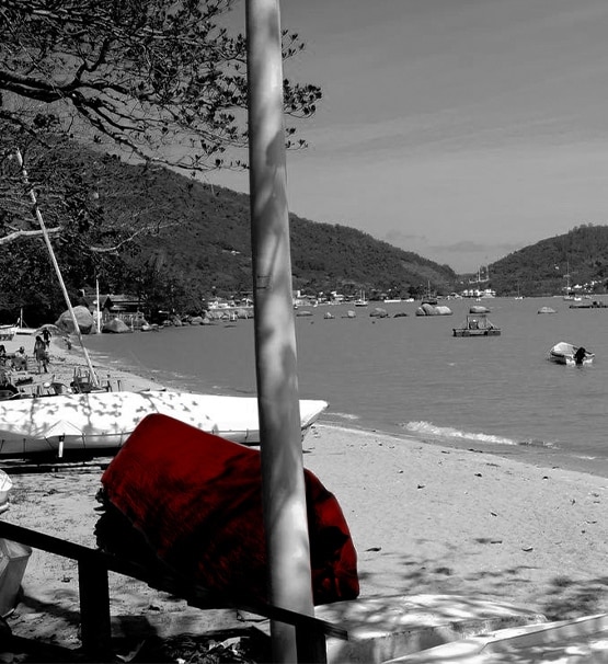 A imagem mostra uma praia em Florianópolis, onde barcos estão na areia.