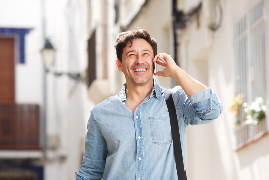 A imagem mostra um homem sorridente ligando para alguém com seu celular. A imagem ilustra o texto de 
