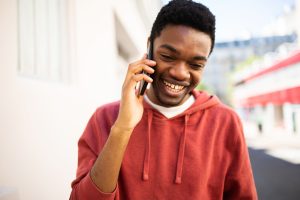 A imagem mostra um homem jovem, sorrindo, enquanto usa o celular em seu ouvido e ilustra o texto: Como Obter Igualdade de Direitos para Cidadão Português da Koetz Advocacia.