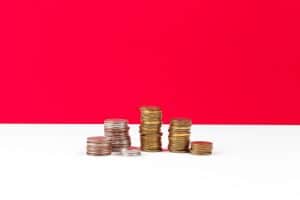 A imagem mostra pilhas de moedas sobre uma mesa e ilustra o texto: Inheritance tax in Brazil da Koetz Advocacia.
