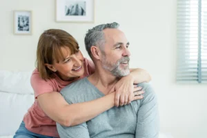 A imagem mostra um casal de meia-idade, abraçados, dentro de sua casa, enquanto sorriem. Ilustra o texto sobre tempo de serviço.