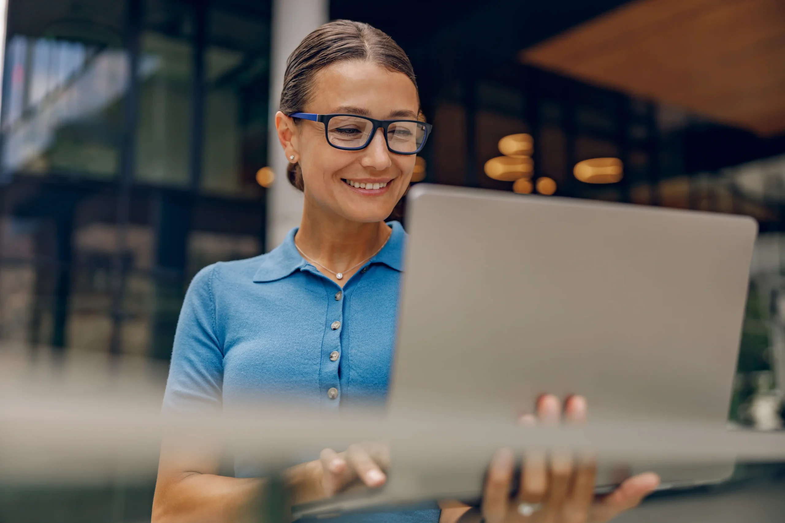 A imagem mostra uma mulher sorridente, utilizando um laptop. Ilustra o texto sobre alíquotas do INSS.