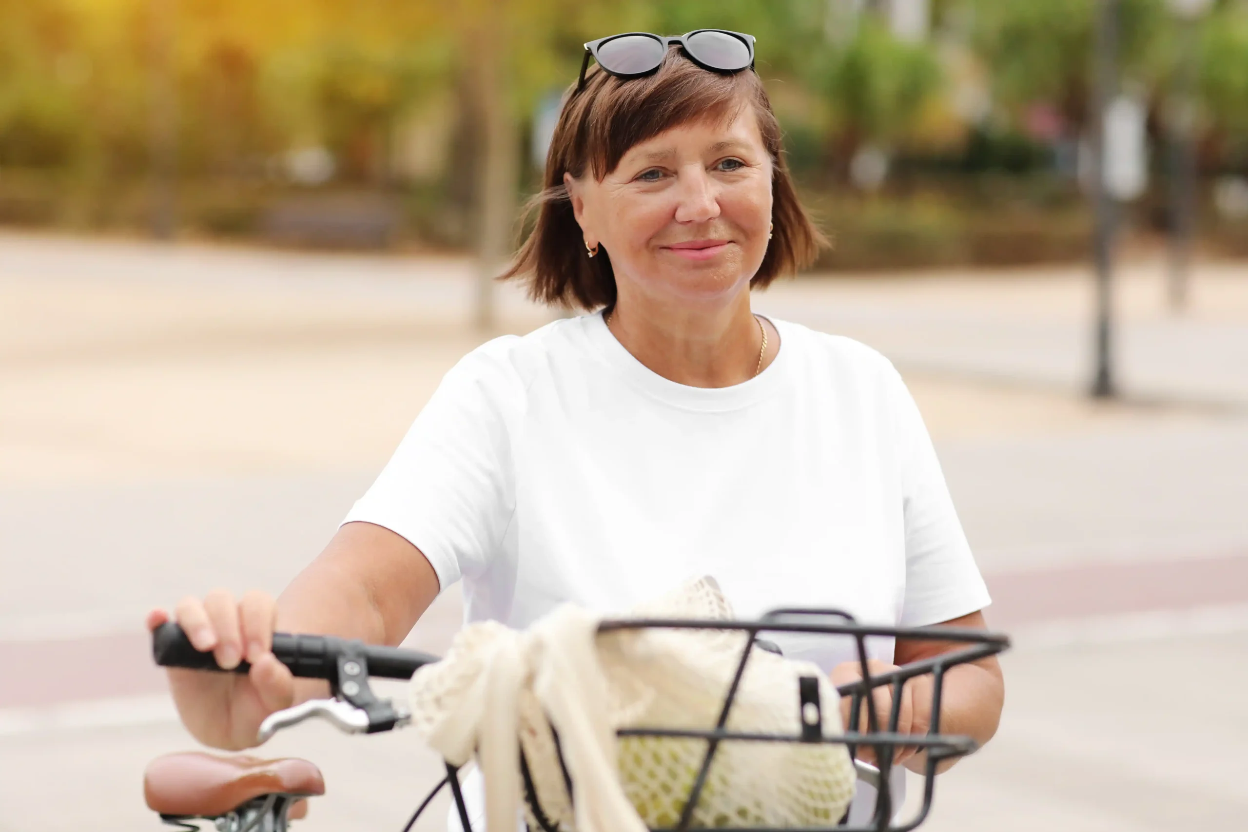 A imagem mostra uma mulher de meia-idade, ao ar livre, com sua bicicleta. Ilustra o texto sobre cálculo da aposentadoria por idade.