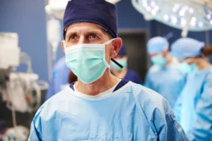 A imagem mostra um cirurgião maduro, com máscara e roupas cirúrgicas, pronto para operação. Ilustra o texto sobre Aposentadoria Especial do Cirurgião.