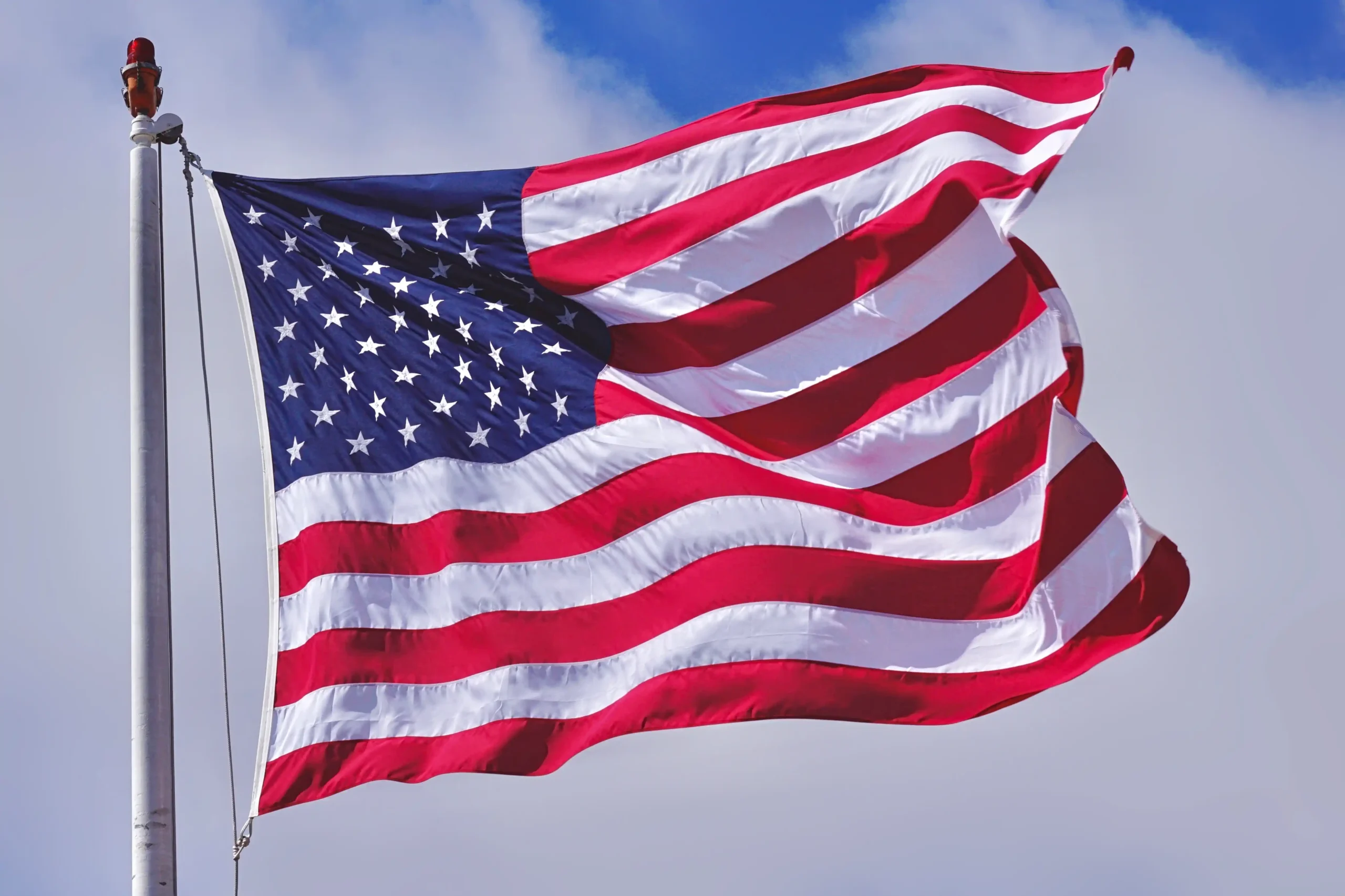 A imagem mostra a bandeira dos Estados Unidos da América, hasteada, balançando com o vento. Ilustra o texto sobre Acordo de Previdência Estados Unidos.