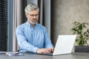A imagem mostra um homem de meia-idade trabalhando em seu laptop, concentrando. Ilustra o texto sobre pagar INSS atrasado de autônomo.