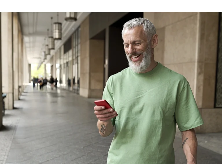 A imagem mostra um homem maduro sorridente, olhando para o seu celular. A imagem ilustra um texto de Koetz Advocacia.
