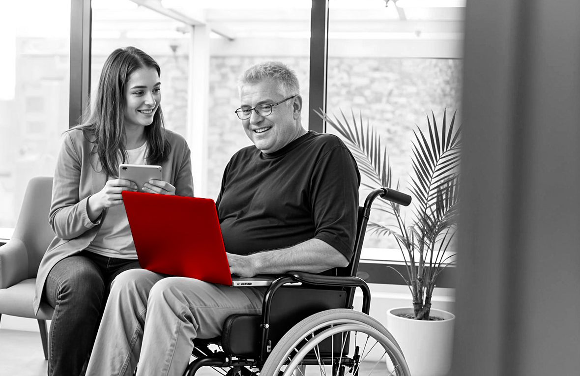 A imagem mostra um homem de meia-idade, cadeirante, utilizando o laptop, que está no seu colo. Do seu lado, sentada, está sua filha, com um tablet nas mãos. Ambos sorriem.