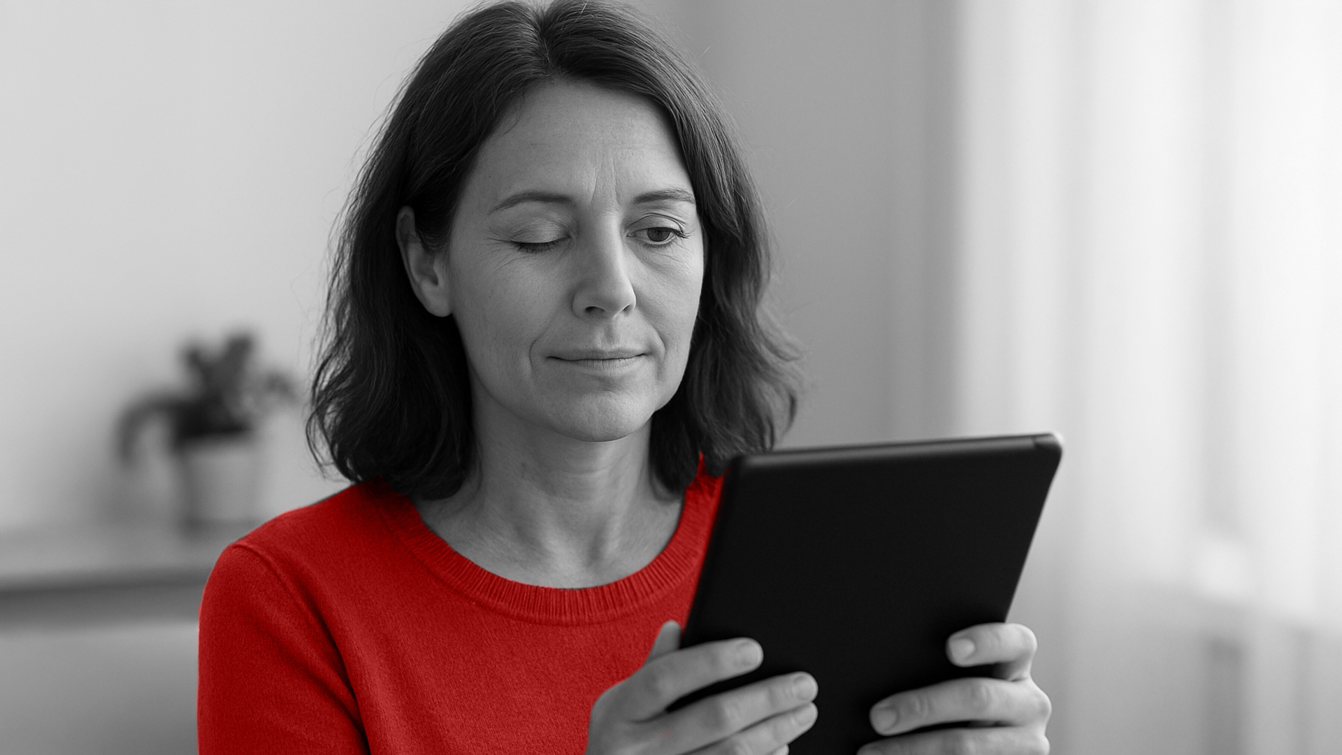 A imagem mostra uma mulher de meia-idade, cega de um olho, segurando um tablet.