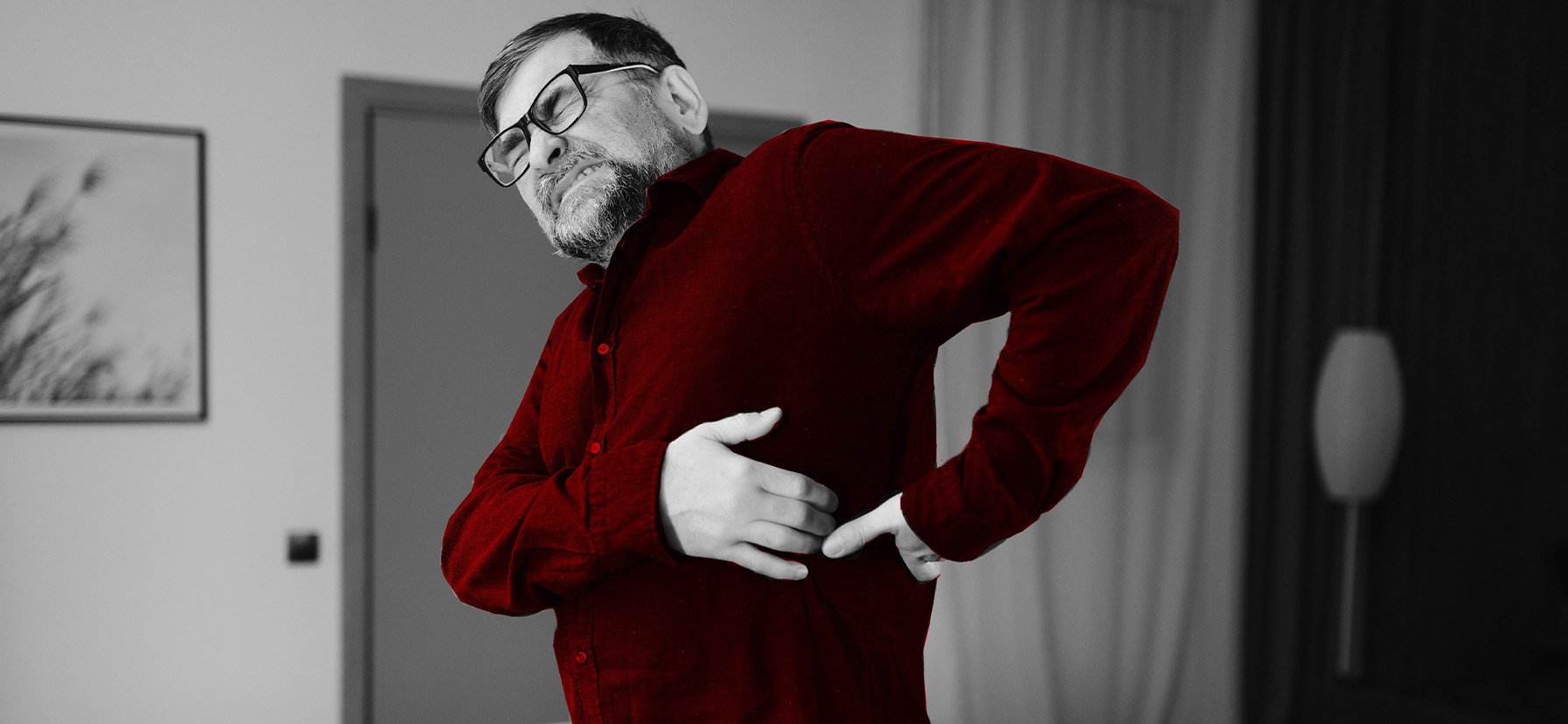 A imagem mostra um homem de meia-idade, em pé, com dores na coluna.