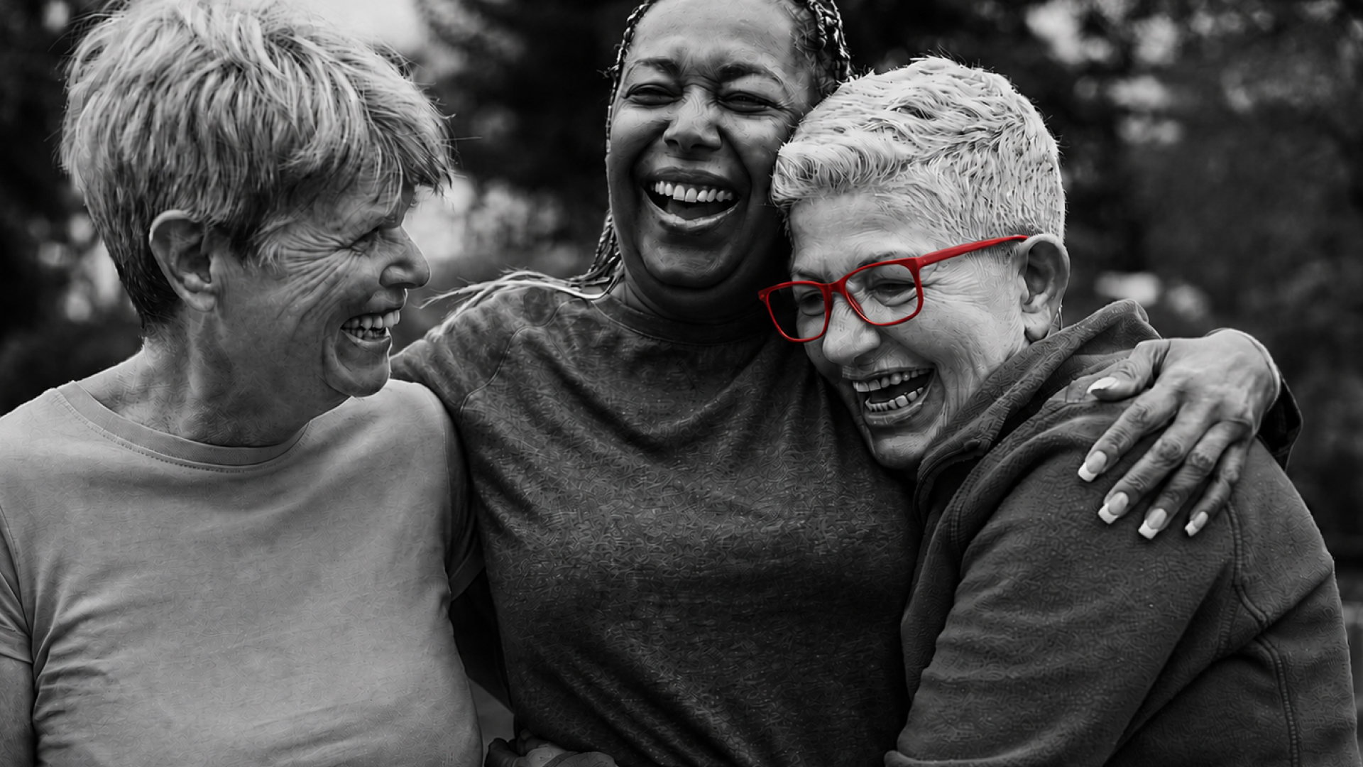 A imagem mostra três amigas de meia-idade, abraçadas e sorrindo.