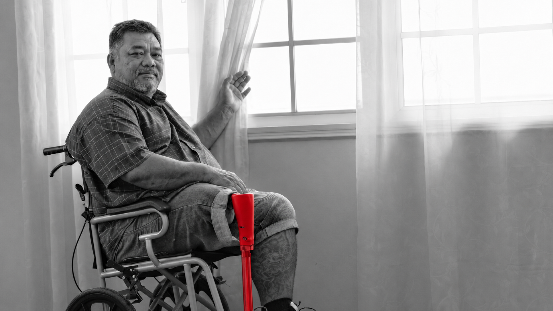 A imagem mostra um homem de meia-idade, sentando em uma cadeira de rodas, com uma prótese em uma de suas pernas.